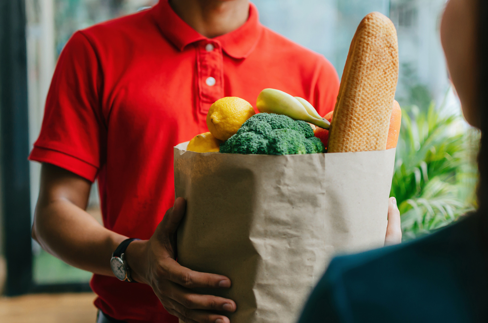 handsome food delivery service man red shirt holding fresh food set bag customer door home express delivery